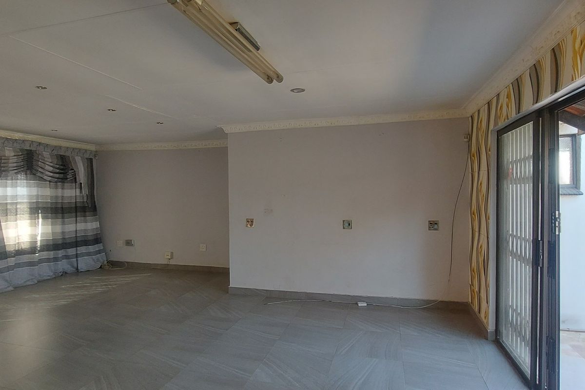 Spacious, empty living area featuring tiled flooring, recessed lighting, and a sliding glass door providing access to the exterior.