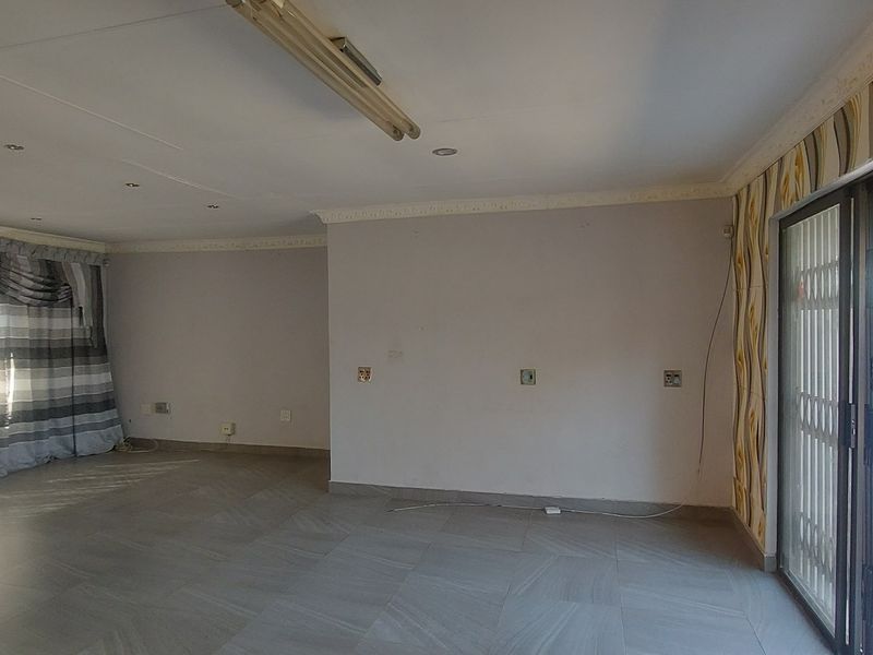 Spacious, empty living area featuring tiled flooring, recessed lighting, and a sliding glass door providing access to the exterior.
