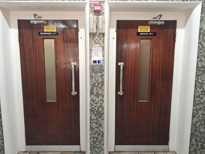 A communal hallway area featuring dedicated passenger and service lift access with mosaic tiled wall finishes.