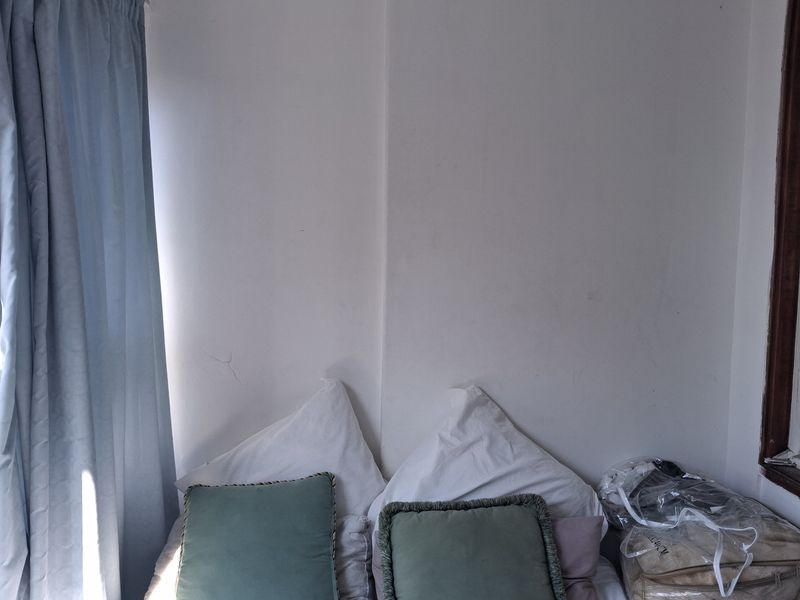 A bedroom corner featuring plain white walls with a visible hairline crack and blue curtains.