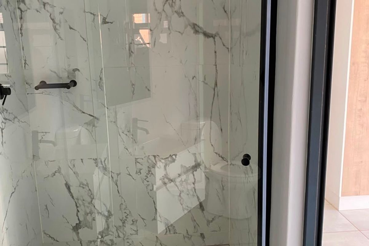 Modern bathroom featuring a walk-in shower with marble-look wall tiles, black frame detailing, and a square floor drain.