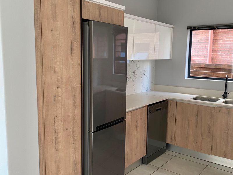 Modern kitchen featuring wood-grain and white cabinetry, marble-look splashback, integrated dishwasher, and contemporary black fixtures with tiled flooring.