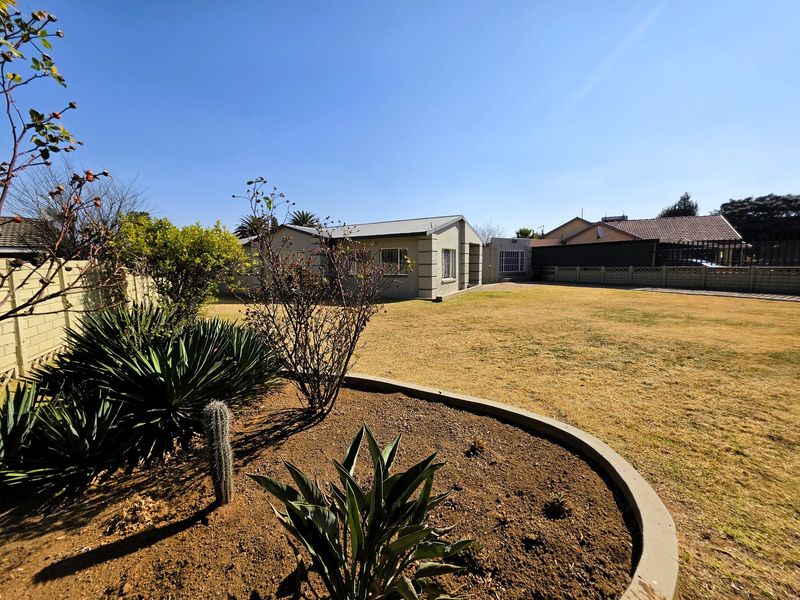 A spacious rear garden featuring a landscaped garden bed with concrete curbing and a view of the rear building elevation.
