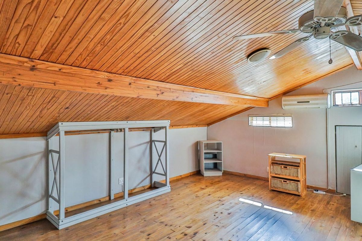 Spacious attic-style bedroom featuring a vaulted timber-clad ceiling, exposed beams, timber flooring, and a split-system air conditioner.