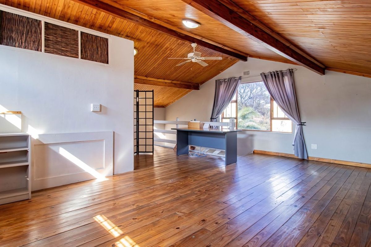 Spacious living area featuring a vaulted timber ceiling with exposed beams, warm timber flooring, and natural light through large windows.