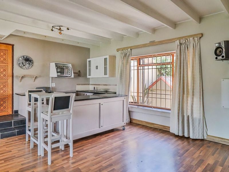 Open plan living and kitchen area featuring exposed ceiling beams, laminate flooring, and a functional kitchen layout with stone countertops.