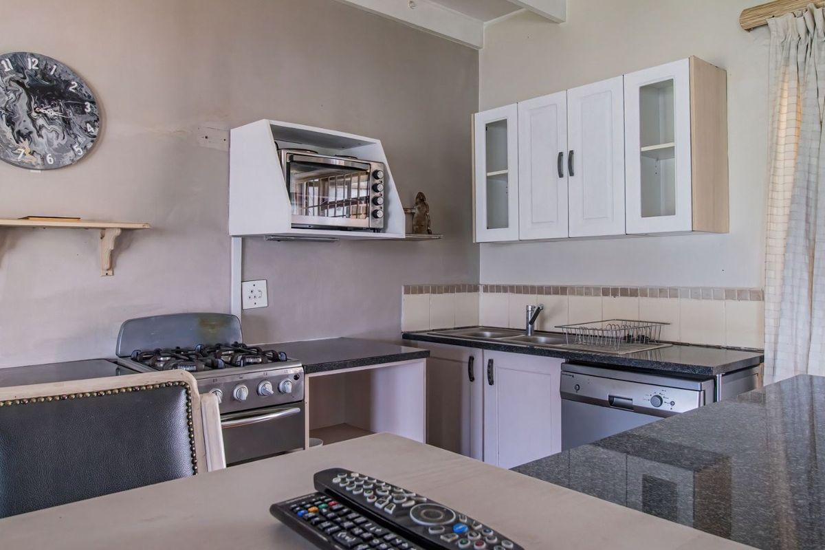 A functional kitchen featuring granite countertops, a gas stove, built-in cabinetry, and a tiled backsplash, offering a practical layout for daily meal preparation.