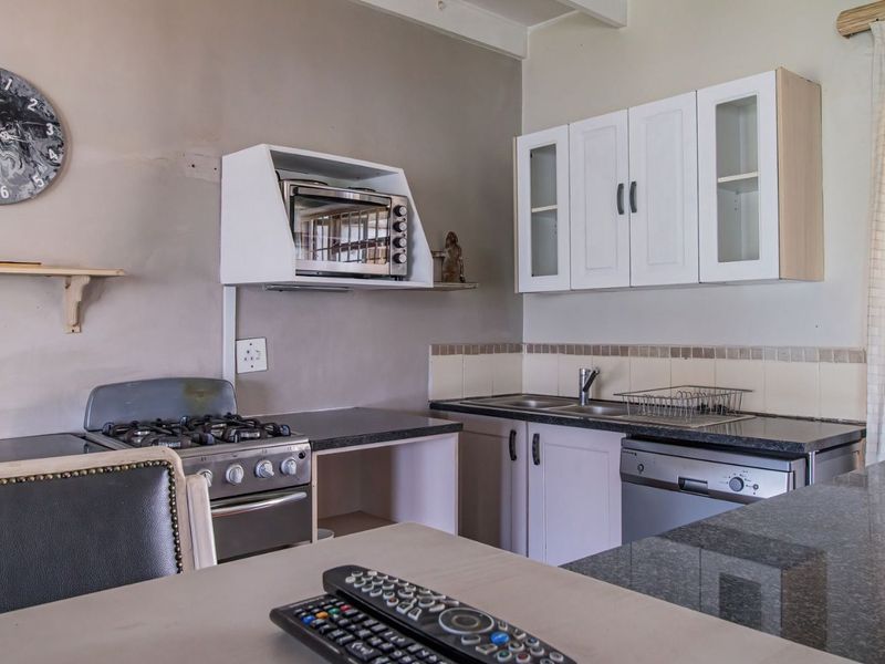 A functional kitchen featuring granite countertops, a gas stove, built-in cabinetry, and a tiled backsplash, offering a practical layout for daily meal preparation.