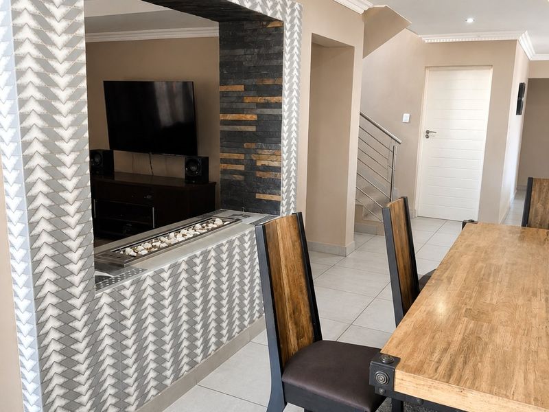Open plan living and dining area featuring a modern built-in fireplace with decorative tiling, tiled floors, and recessed lighting.