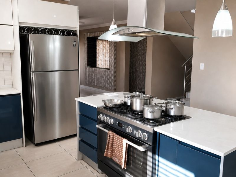Modern kitchen featuring a central island with a gas cooktop, stainless steel extractor fan, stone countertops, and contemporary blue and white cabinetry.