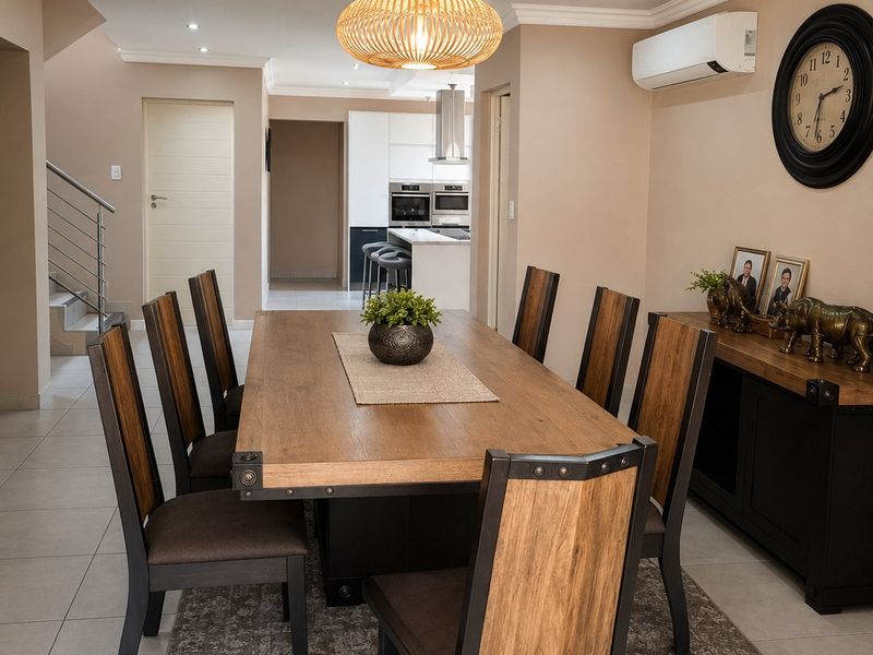 Open-plan dining area featuring tiled floors, a recessed ceiling with pendant lighting, and a split-system air conditioner, with a view into the modern kitchen.
