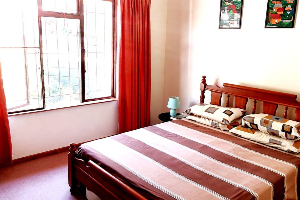 A bedroom featuring carpeted flooring and a window fitted with security bars, providing natural light.