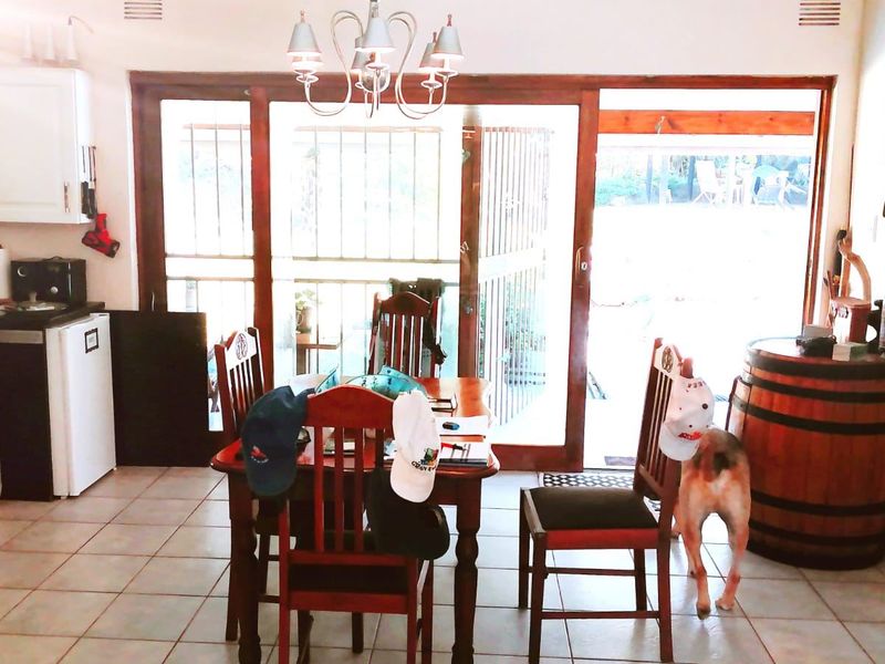 Open plan living and dining area featuring tiled floors, kitchen cabinetry with granite countertops, and large sliding glass doors leading to the outdoor space.