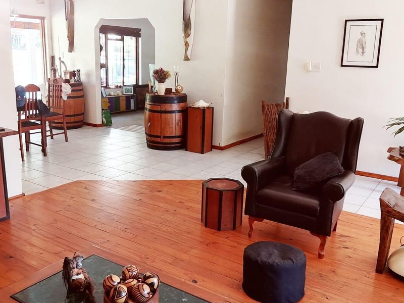 Open plan living area featuring a combination of warm timber flooring and neutral ceramic tiles, connected by a characterful architectural archway.