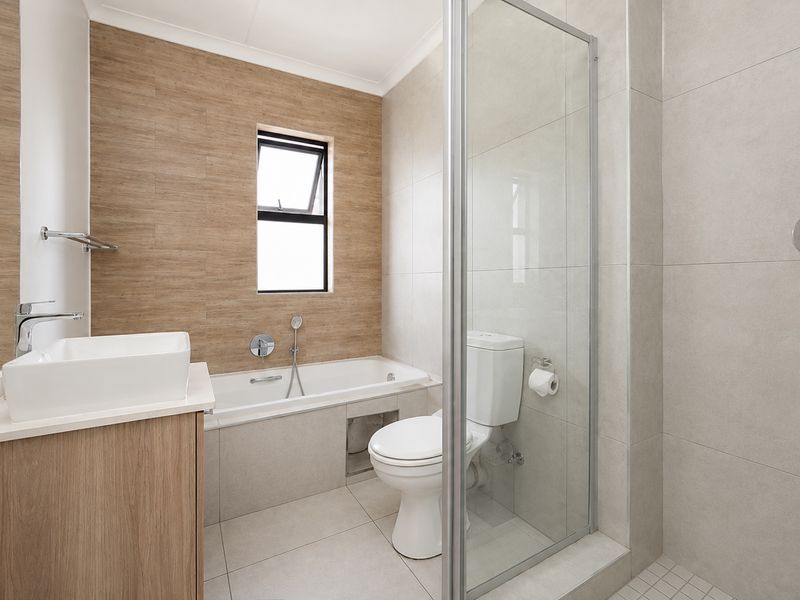 Modern bathroom featuring a built-in bathtub, separate glass-enclosed shower, vanity with vessel sink, and neutral tiled finishes throughout.