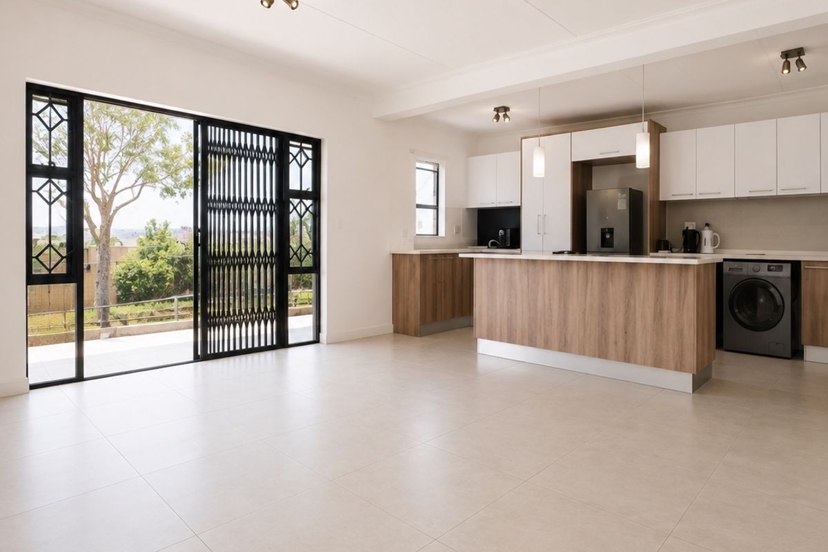 Spacious open-plan living and kitchen area featuring modern cabinetry, a central island, tiled flooring, and large sliding doors leading to an outdoor space.