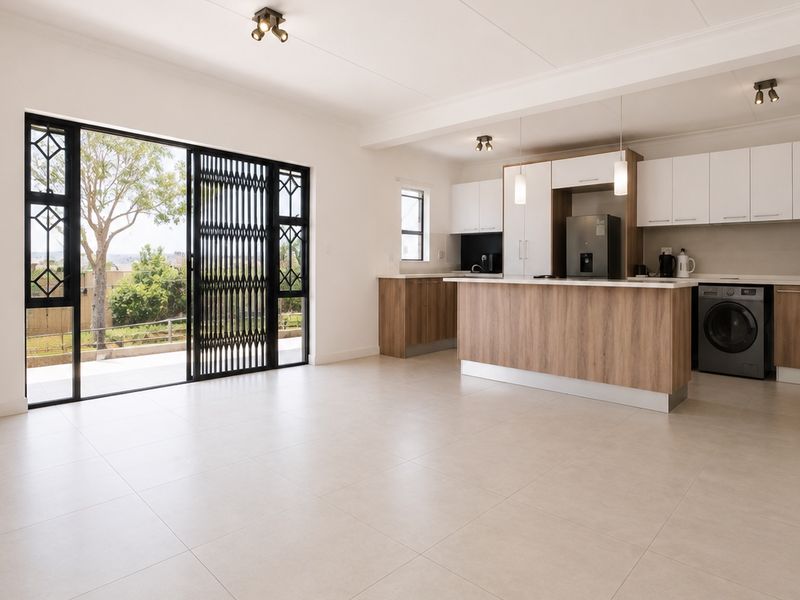 Spacious open-plan living and kitchen area featuring modern cabinetry, a central island, tiled flooring, and large sliding doors leading to an outdoor space.