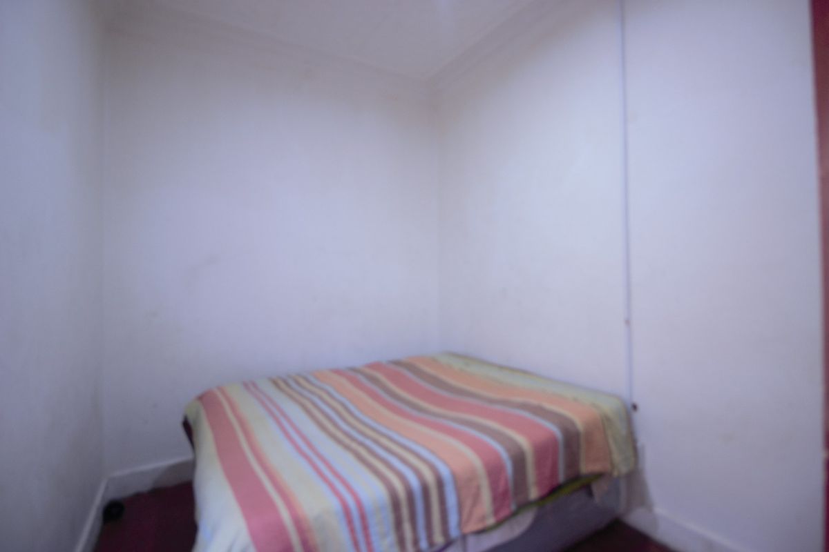 A small bedroom featuring plain walls and carpeted flooring, requiring cosmetic updates to improve its overall appeal.