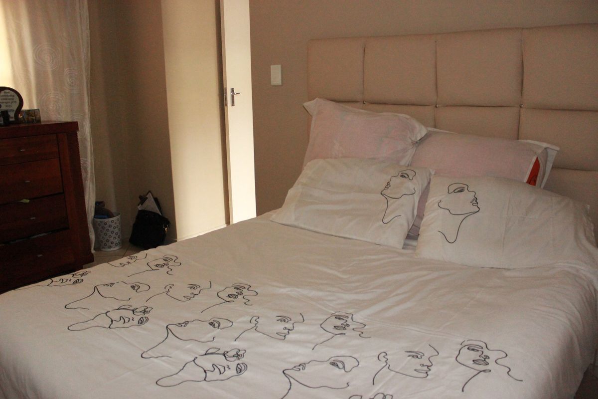 A bedroom featuring a neutral color palette and a large upholstered headboard.