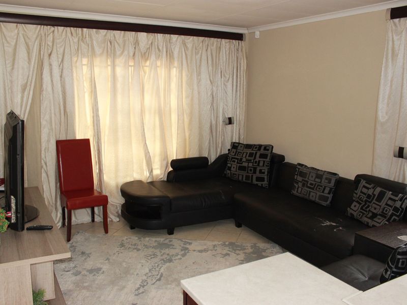 A living room area featuring tiled flooring and full-length window curtains.