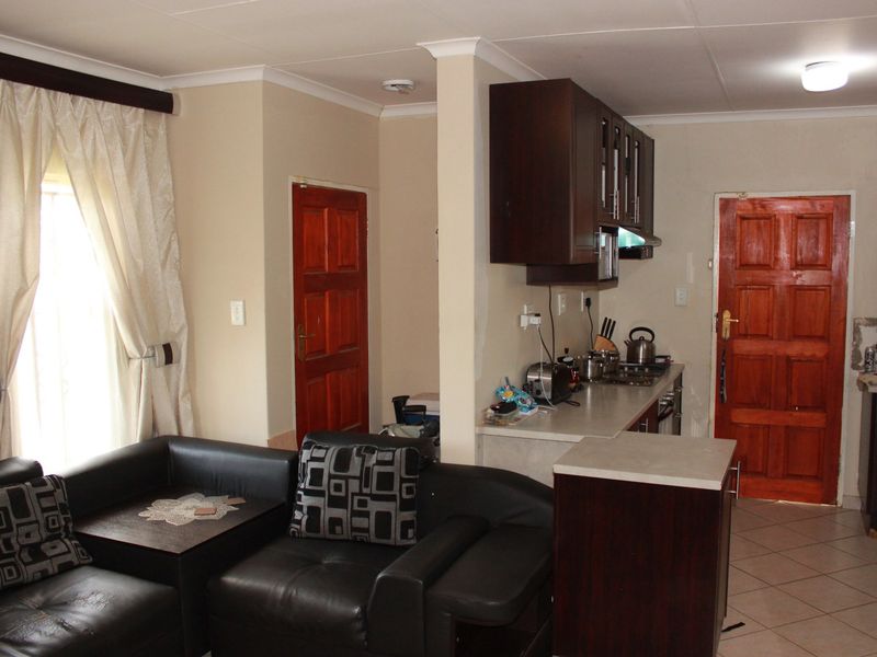 Open plan living and kitchen area featuring dark wood cabinetry, tiled flooring, and solid wood doors, offering a functional layout for daily living.
