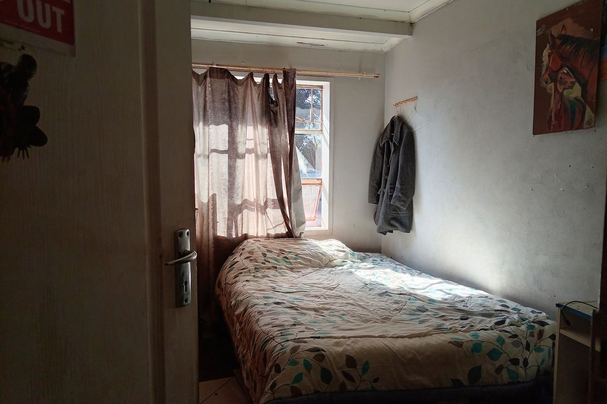 A compact bedroom featuring a window with natural light, requiring cosmetic updates to the walls and ceiling to improve the overall living space.