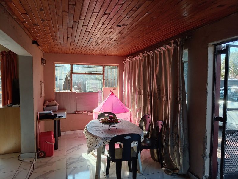 Living area featuring a timber tongue and groove ceiling and tiled flooring, requiring cosmetic updates to wall finishes and general maintenance.