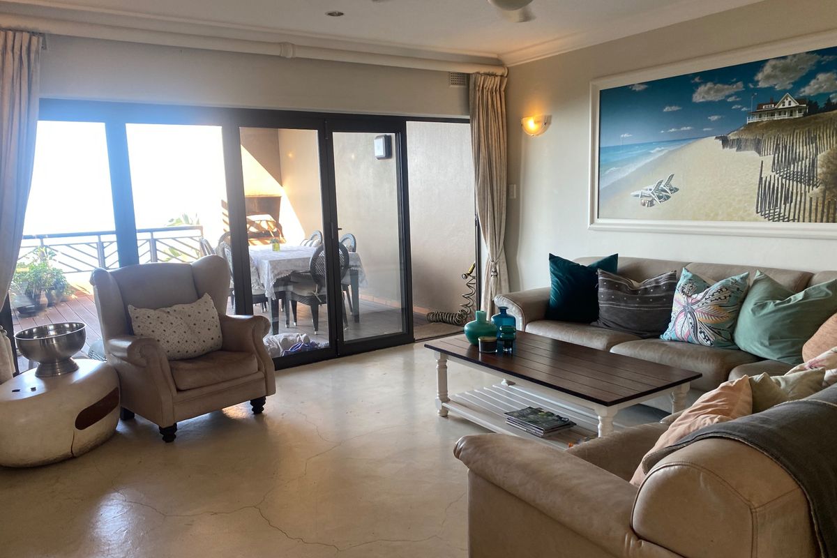 A comfortable living room featuring polished concrete floors, a ceiling fan, and large sliding glass doors that open onto a private balcony.