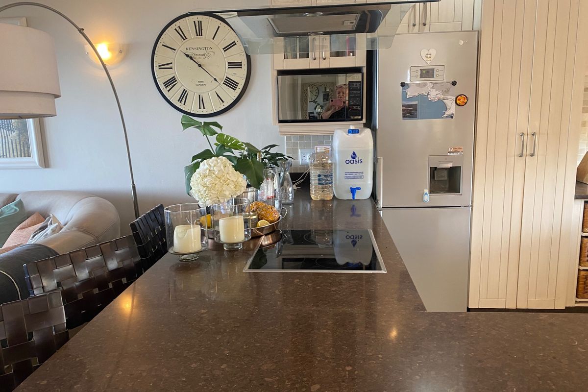 A functional kitchen area featuring a stone countertop, induction hob, built-in microwave, and integrated cabinetry, providing a practical and well-organized cooking space.