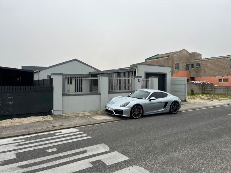 Front exterior view of the property featuring a perimeter wall, metal fencing, and a paved driveway entrance.