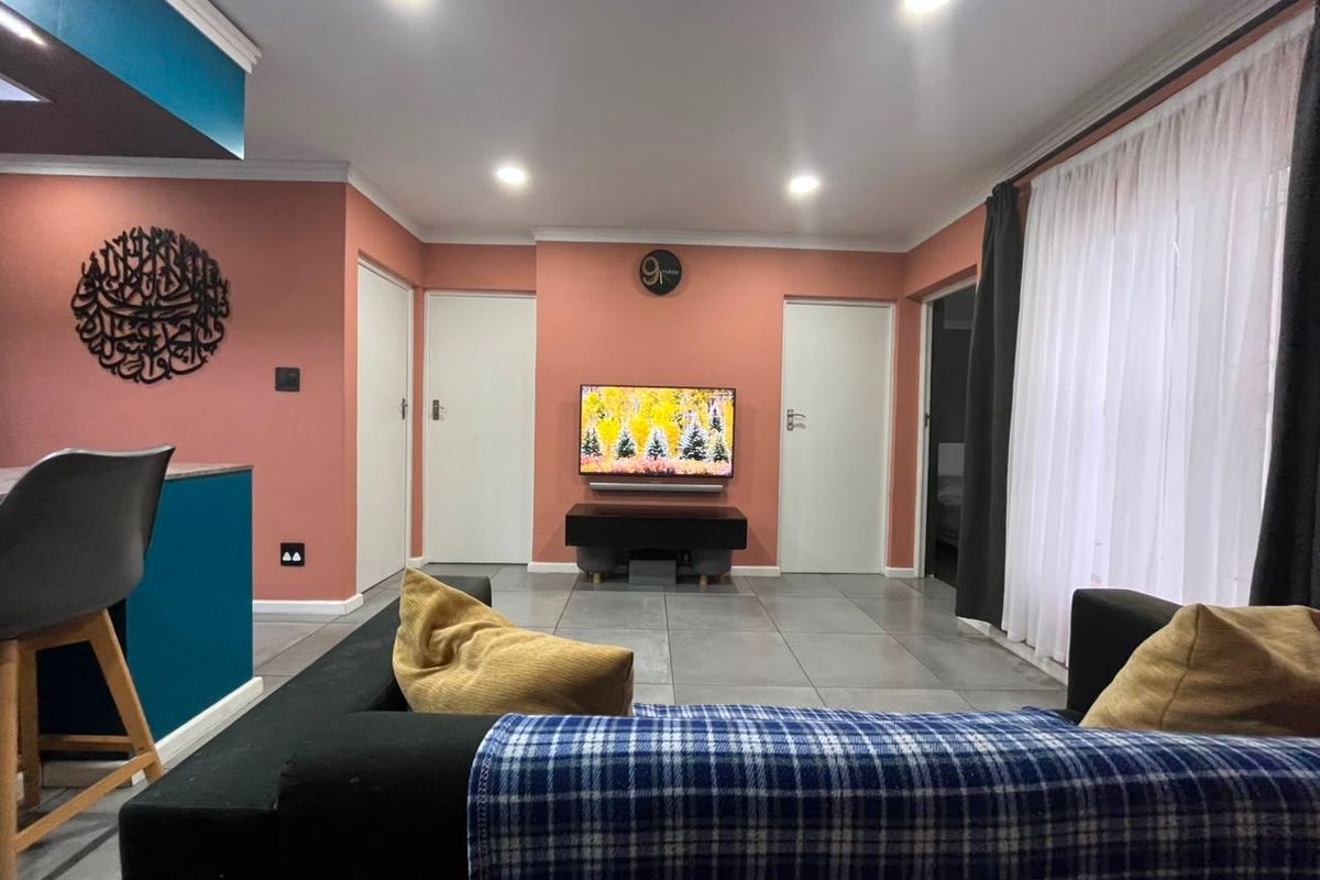 A modern living room featuring tiled flooring, recessed downlighting, and a contemporary color scheme with multiple internal access doors.
