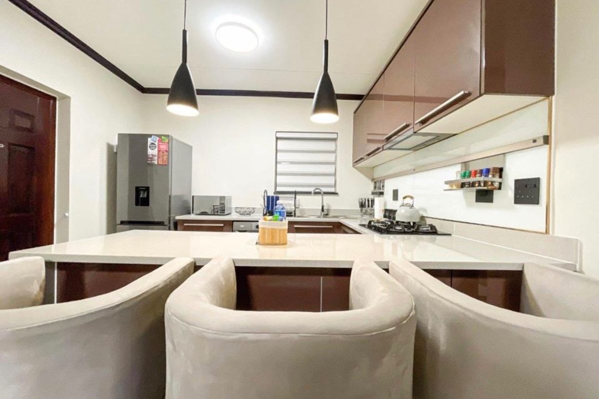 Modern kitchen featuring sleek brown cabinetry, stone countertops, a gas hob, and stylish pendant lighting, creating a functional and contemporary cooking space.