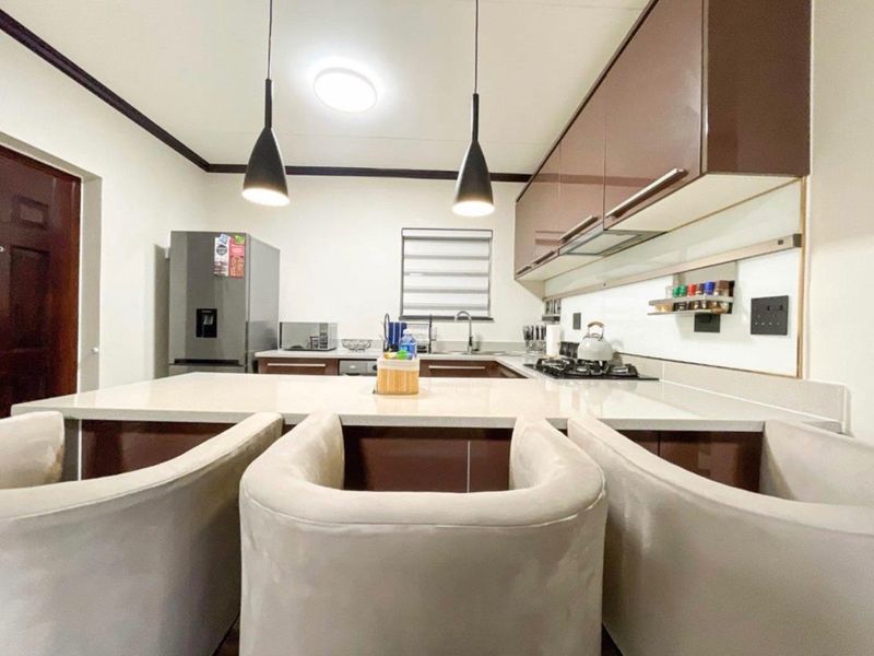 Modern kitchen featuring sleek brown cabinetry, stone countertops, a gas hob, and stylish pendant lighting, creating a functional and contemporary cooking space.