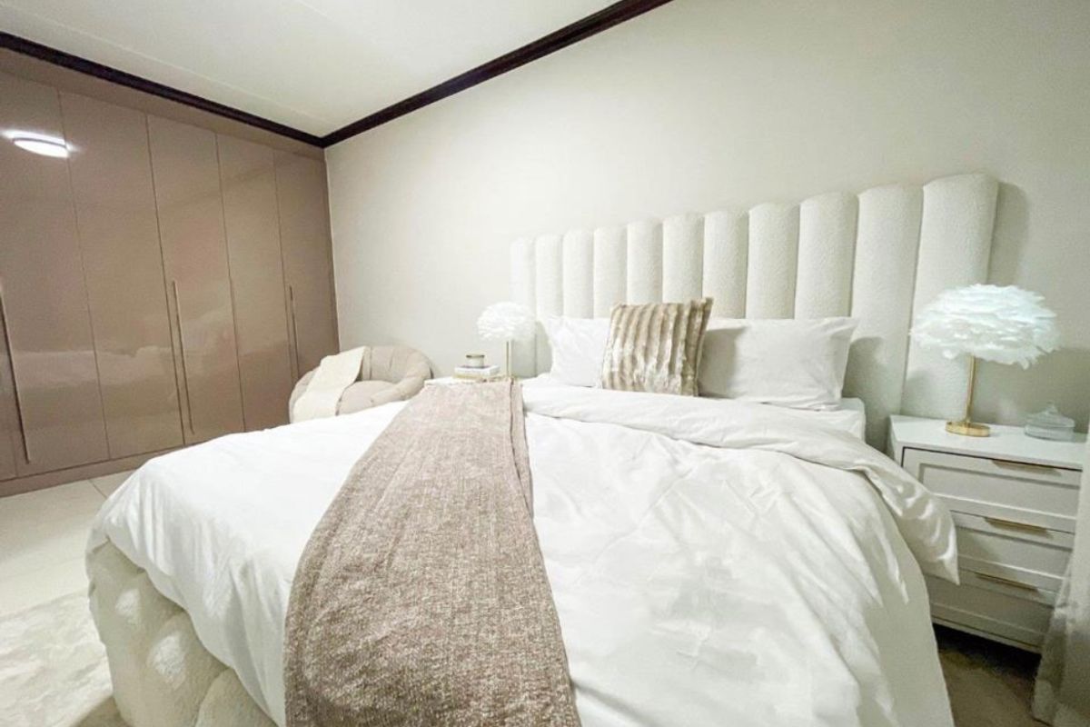 A well-maintained bedroom featuring neutral tones, built-in floor-to-ceiling cupboards, and a coved ceiling finish.