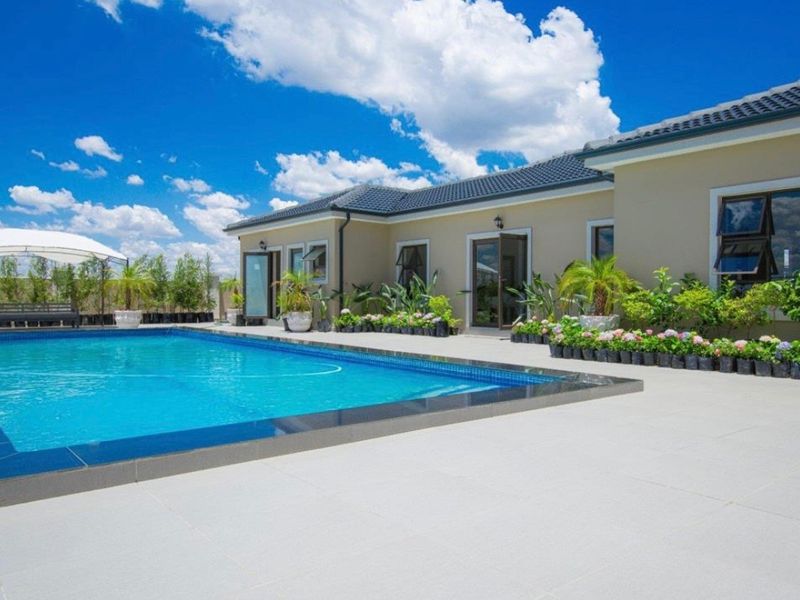 A well-maintained outdoor pool area featuring a tiled deck, modern swimming pool, and direct access to the residence through multiple sets of french doors.