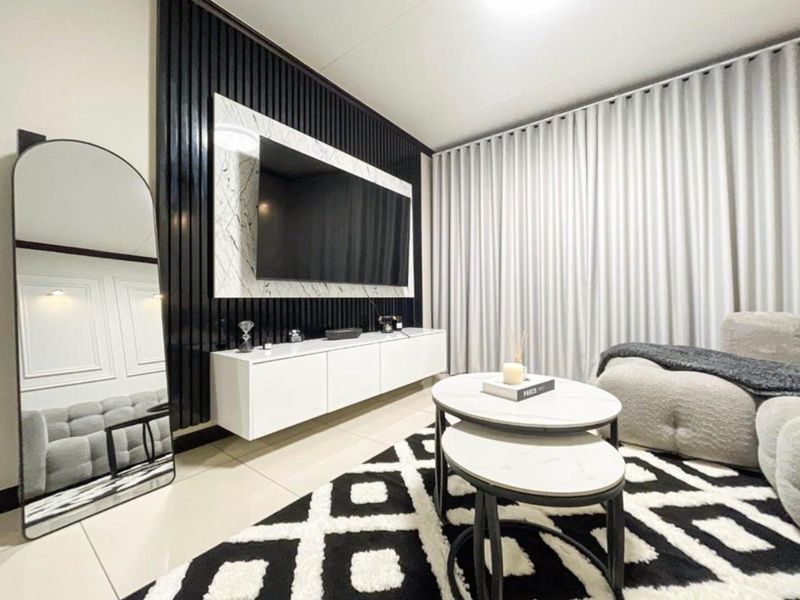 Modern living room featuring a striking black vertical slat feature wall with integrated marble paneling, wall-mounted cabinetry, and neutral floor-to-ceiling curtains.