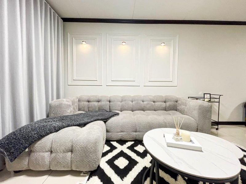 A well-maintained living room featuring decorative wall niches with integrated accent lighting and elegant crown molding.