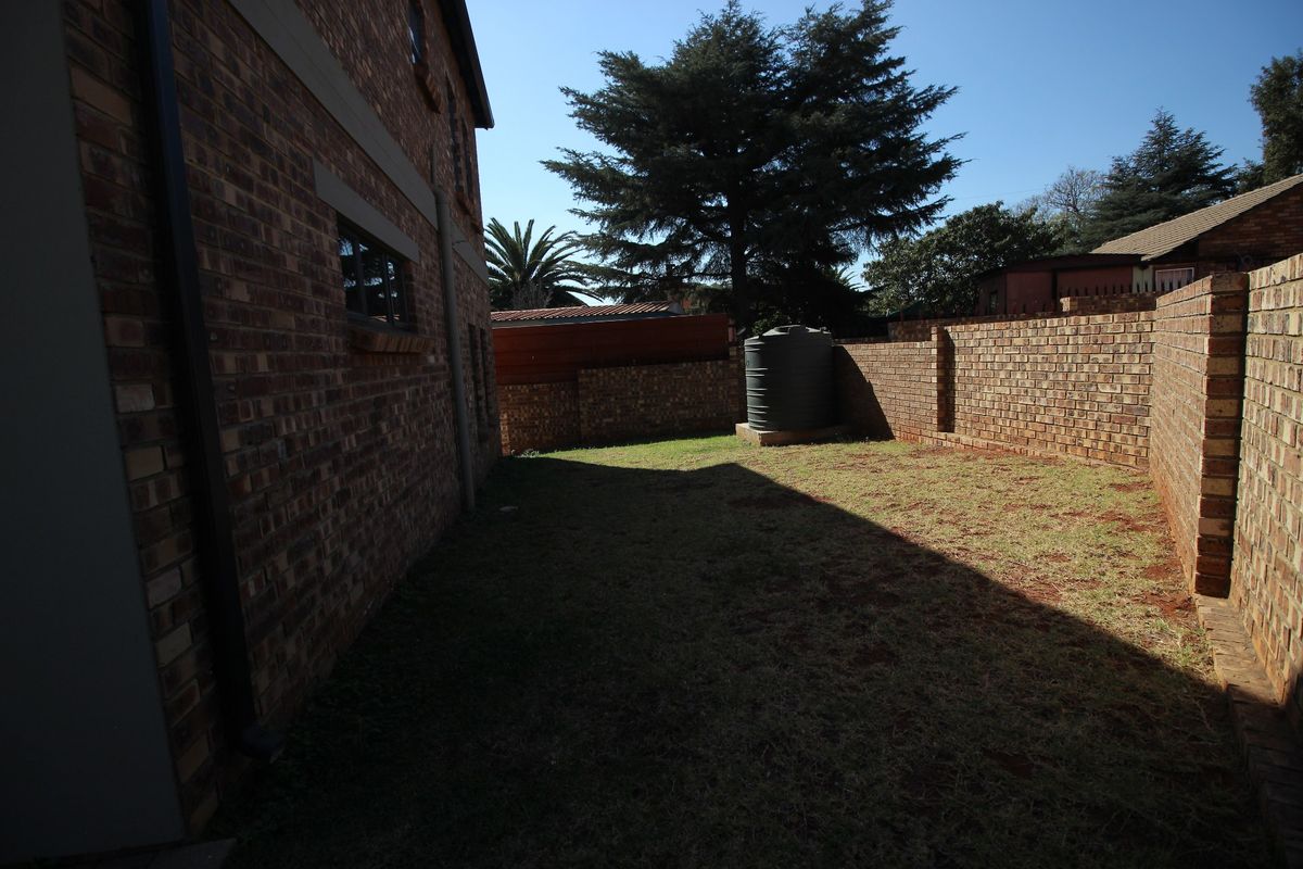 A private rear garden area featuring face brick exterior walls, a boundary wall, and a water storage tank.