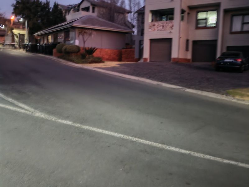 A street-level view of a multi-story townhouse complex featuring paved driveways and integrated garage doors at dusk.