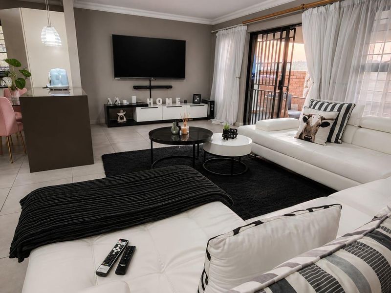 Modern open-plan living area featuring tiled floors, a kitchen island with pendant lighting, and sliding glass doors leading to an outdoor space.