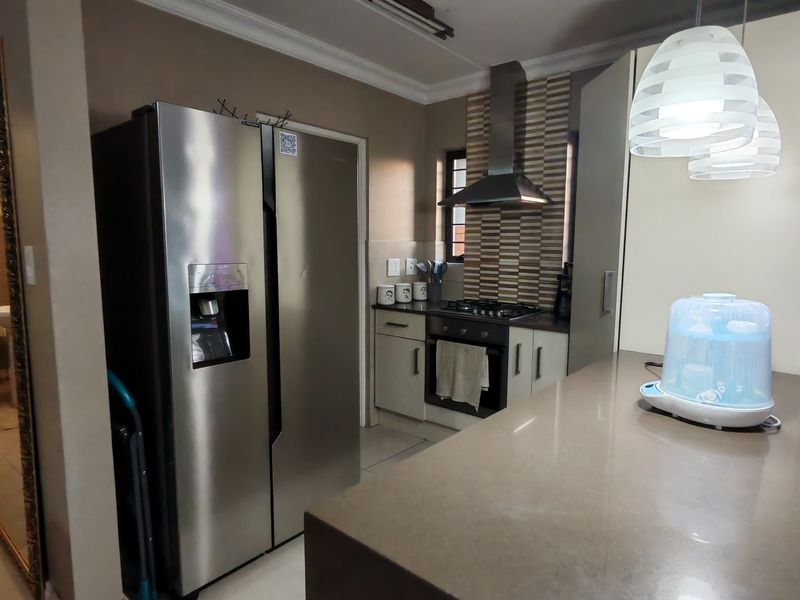 Modern kitchen featuring stone countertops, built-in oven, gas hob, stainless steel extractor fan, and tiled flooring with neutral cabinetry.