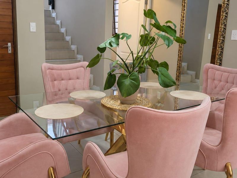 A well-maintained dining area featuring tiled flooring, crown molding, and an open staircase with a modern metal balustrade.