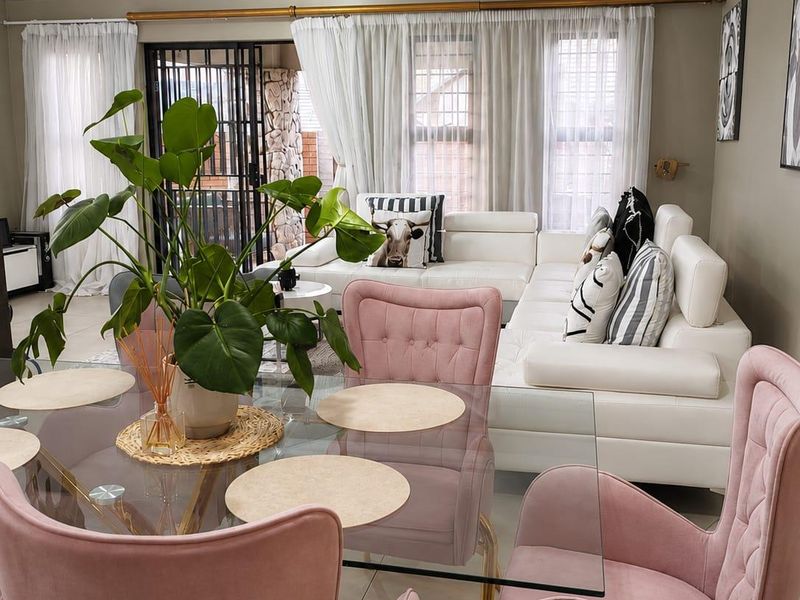 A bright open-plan living and dining area featuring tiled floors, crown molding, and large sliding doors leading to an outdoor space.