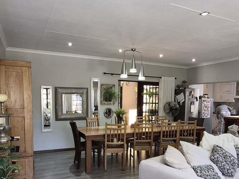 Spacious open-plan living and dining area featuring modern laminate flooring, recessed lighting, and seamless flow to the kitchen and outdoor patio.