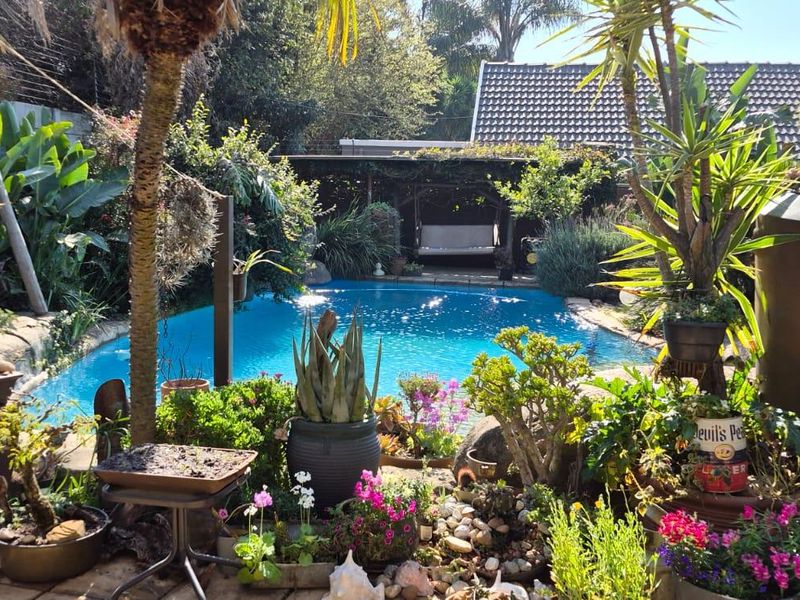 A lush, landscaped backyard featuring a swimming pool and a covered patio area, creating a private outdoor retreat.