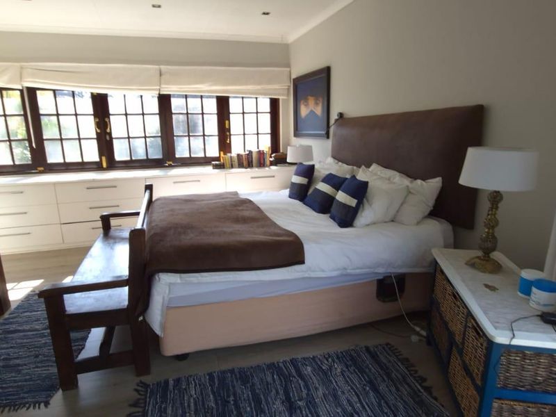 A well-maintained bedroom featuring built-in cabinetry under large timber-framed windows, providing ample storage and natural light.