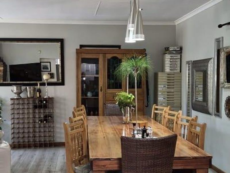 A well-maintained dining area featuring light-toned laminate flooring, coved cornicing, and modern recessed downlighting, creating a bright and functional space for family meals.