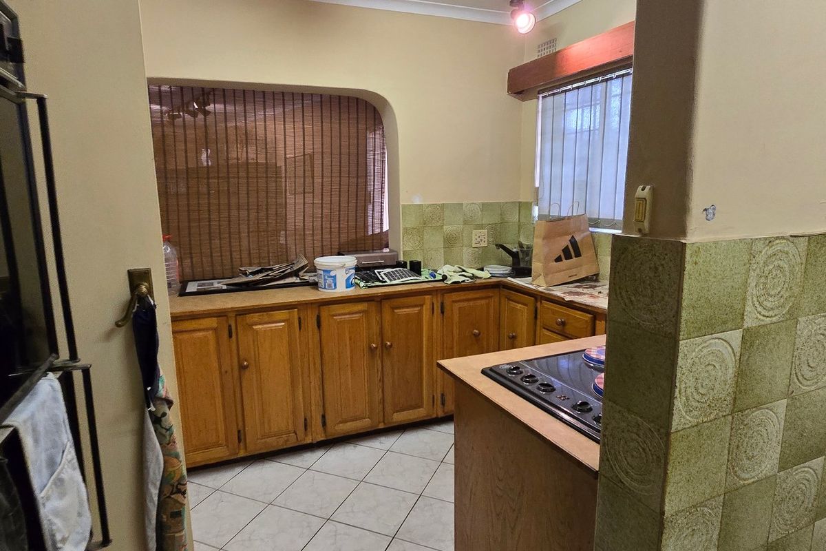 A dated kitchen featuring wooden cabinetry, tiled splashbacks, and built-in cooking appliances, offering potential for a modern renovation.