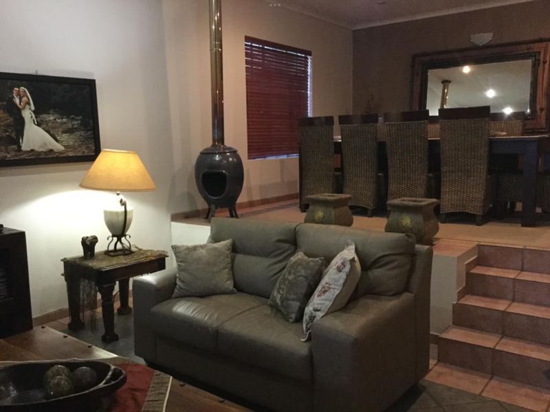 Open plan living and dining area featuring a raised dining platform, tiled staircase, and a prominent freestanding fireplace.