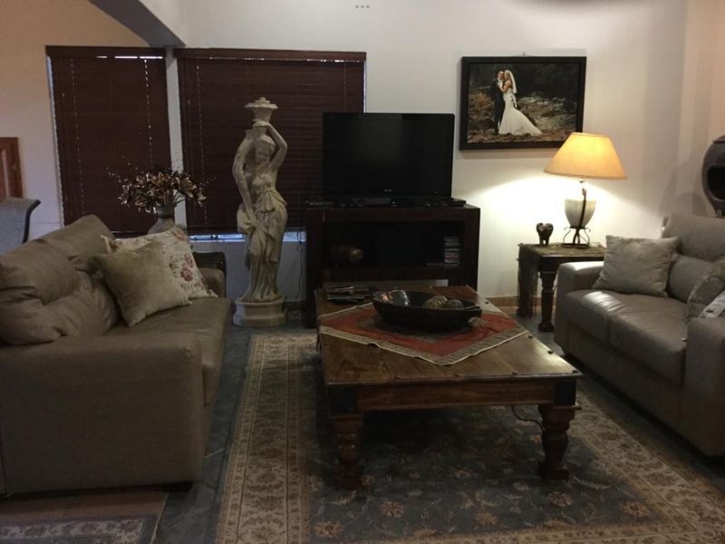 A comfortable living room featuring tiled flooring and wooden blinds, providing a functional space for relaxation and entertainment.